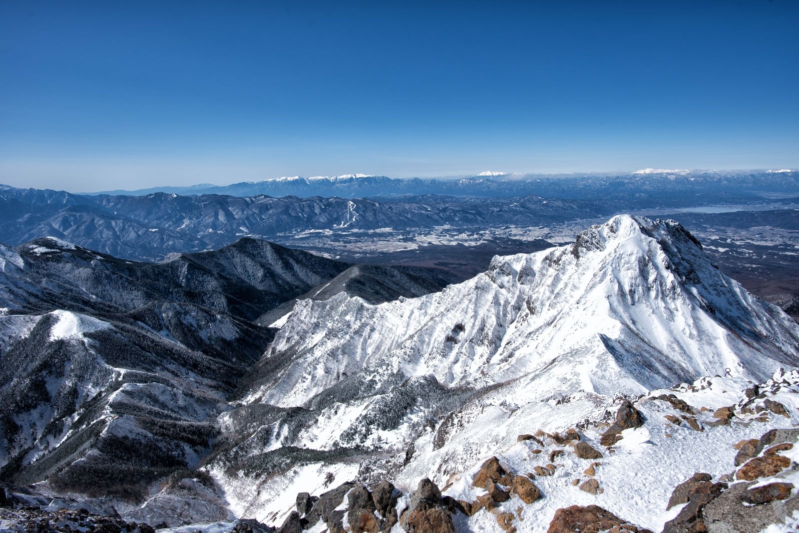 赤岳山頂から見渡す雪化粧した山脈と青空の風景