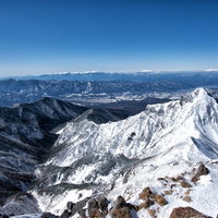 赤岳山頂から見渡す雪山の展望。冬の山々の稜線の写真