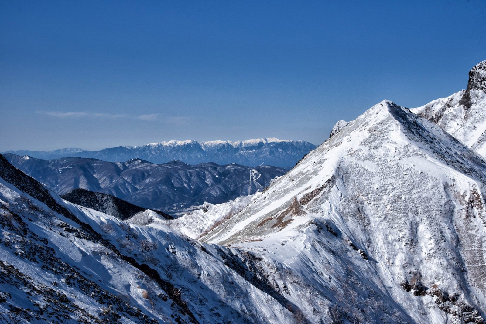 雪に覆われた山頂と遠景の中央アルプス