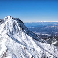 雪に覆われた阿弥陀岳と北アルプスの山並みの写真