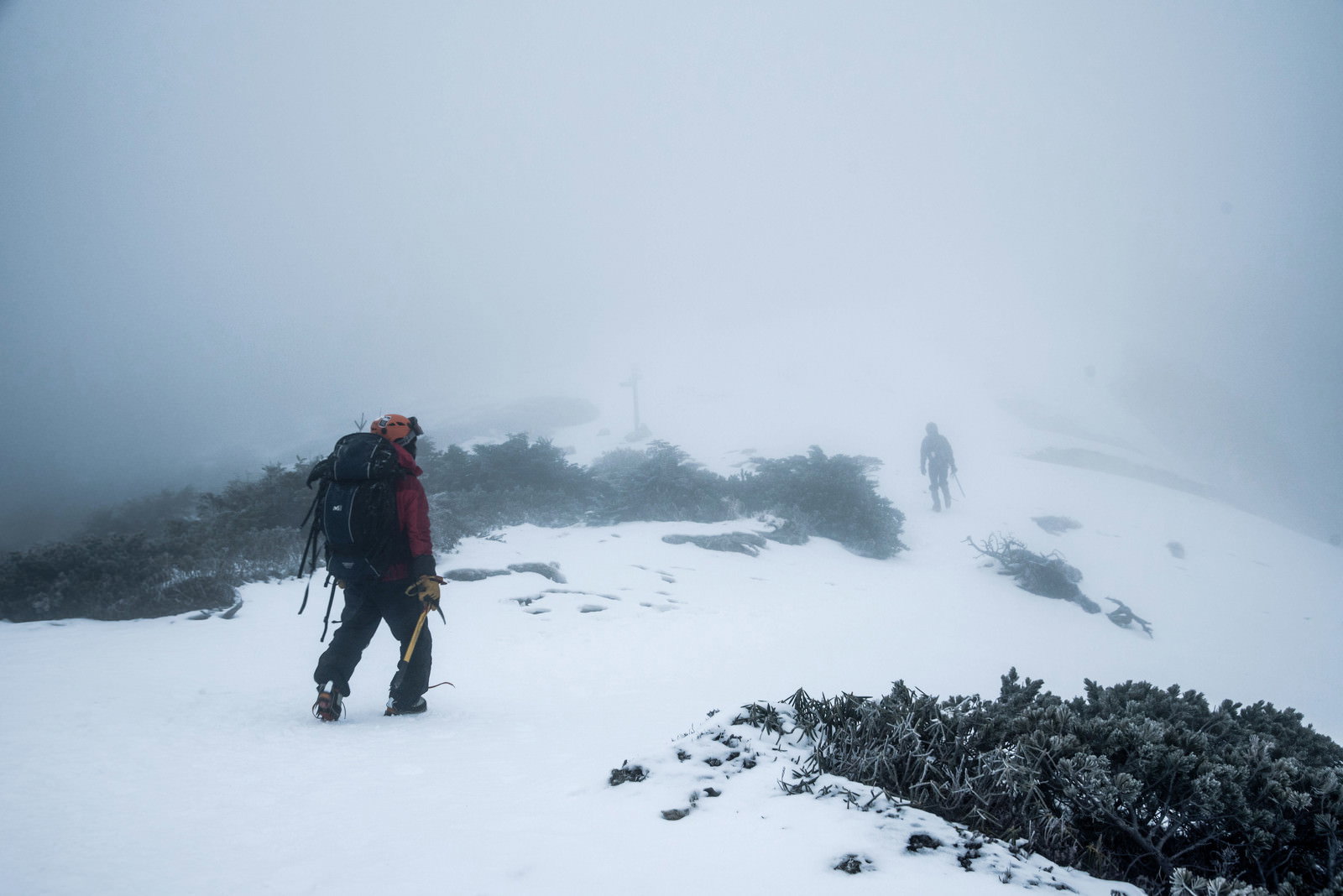ホワイトアウト状態の雪山で山頂を目指して歩く登山者