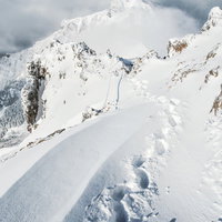 雪山の稜線に続くラッセルの跡と阿弥陀岳（八ヶ岳南部）の写真
