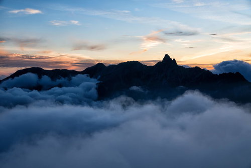 朝焼けに染まる雲海に浮かぶ槍ヶ岳の山岳風景