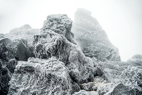 厳冬の岩肌に張り付く氷と霧のモノクロ風景
