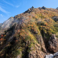紅葉に染まる秋の針ノ木谷の山肌と岩場の登山風景の写真