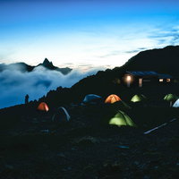大天井岳の朝焼けとテント場に灯るテントの夜景の写真
