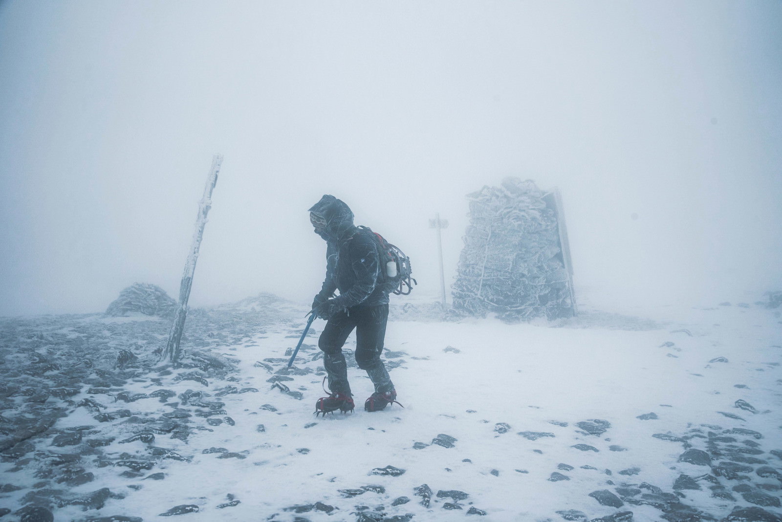 吹雪の雪山で悪天候に耐えながら歩く登山者