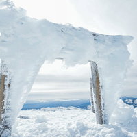 凍り付く鳥居と樹氷に覆われた乗鞍岳剣ヶ峰の山頂の写真