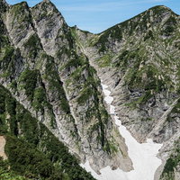 不帰キレット2峰横の雪渓と岩峰の縦走路の写真