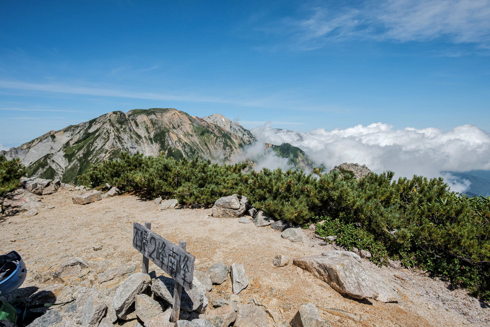 不帰キレット2峰南峰の山頂に立つ指導標と青空に広がる雲