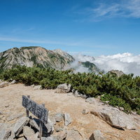 不帰キレット2峰南峰の山頂と指導標、険しい岩稜帯の尾根の写真
