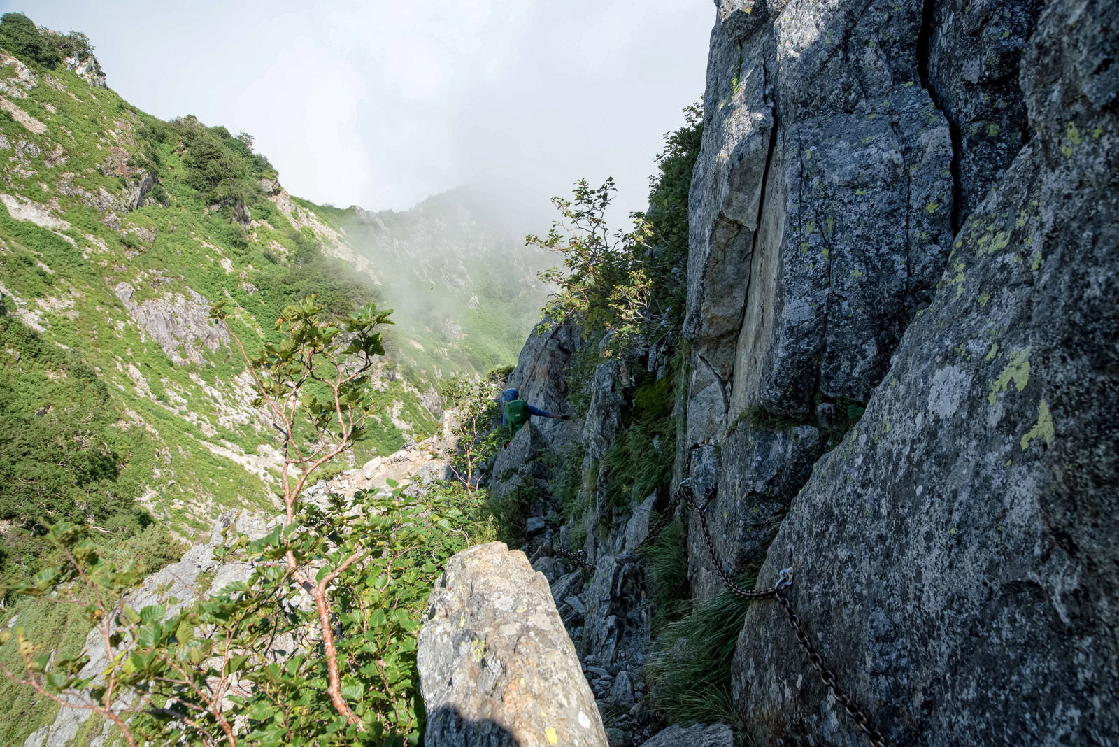 不帰キレット2峰付近の急峻な岩壁で鎖場を登る登山者