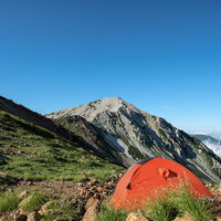 不帰キレットのテント場に設営されたオレンジ色のテントと白馬鑓ヶ岳の写真
