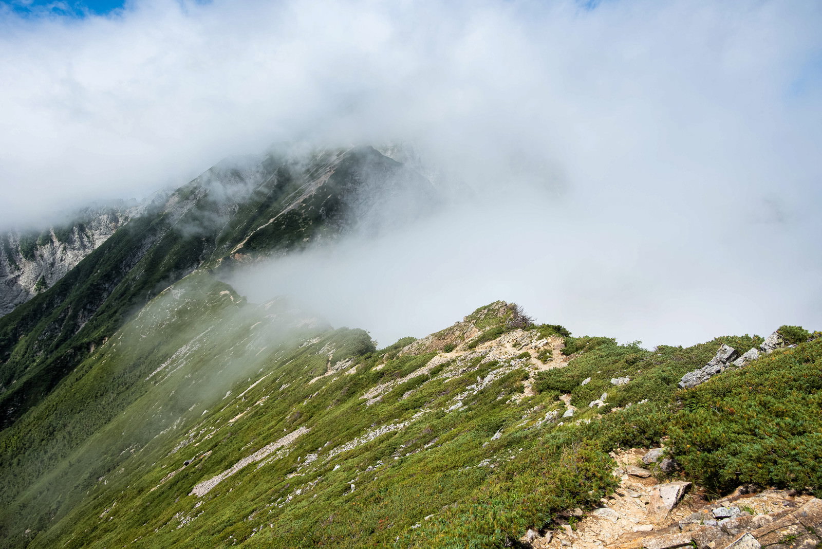 雲と霧に包まれた不帰キレットの稜線を歩く登山道