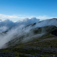 雲の駆け上がる不帰キレットの稜線を歩く登山道の写真