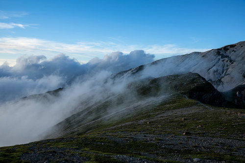 雲の駆け上がる不帰キレットの稜線を歩く登山道