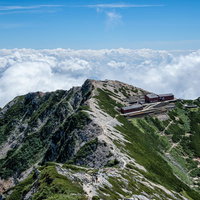 雲海に浮かぶ不帰キレットと唐松山荘の山稜風景の写真