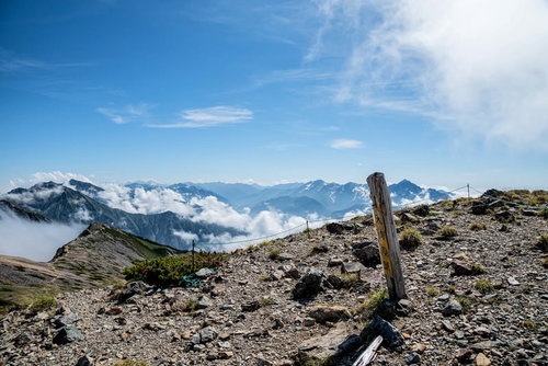 天狗の頭の標識とキレット縦走の登山道を行く登山者の風景