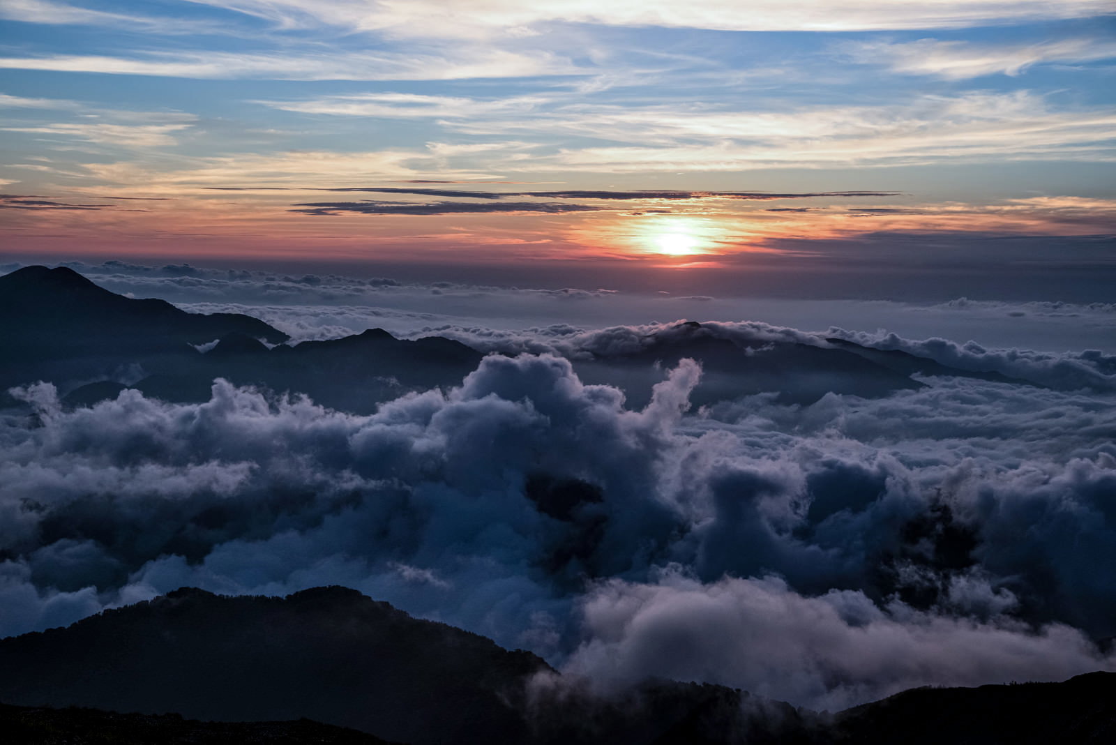 天狗原から見る夕日と雲海に浮かぶ山々のシルエット