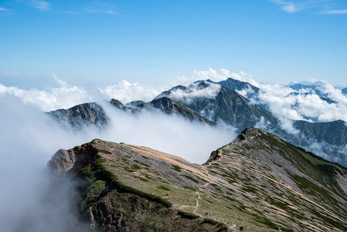 雲海に浮かぶ不帰キレットと天狗背稜の山岳風景