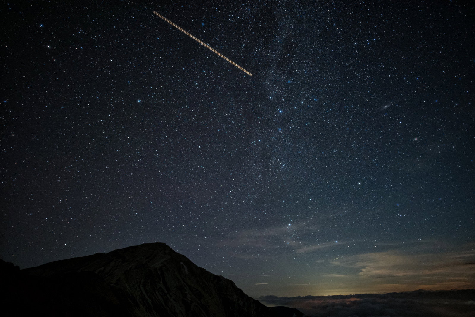 北アルプスの夜空を飛行する航空機と星空が写った写真