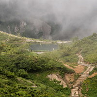 霧に包まれる八方池と不帰キレット、登山道の風景の写真