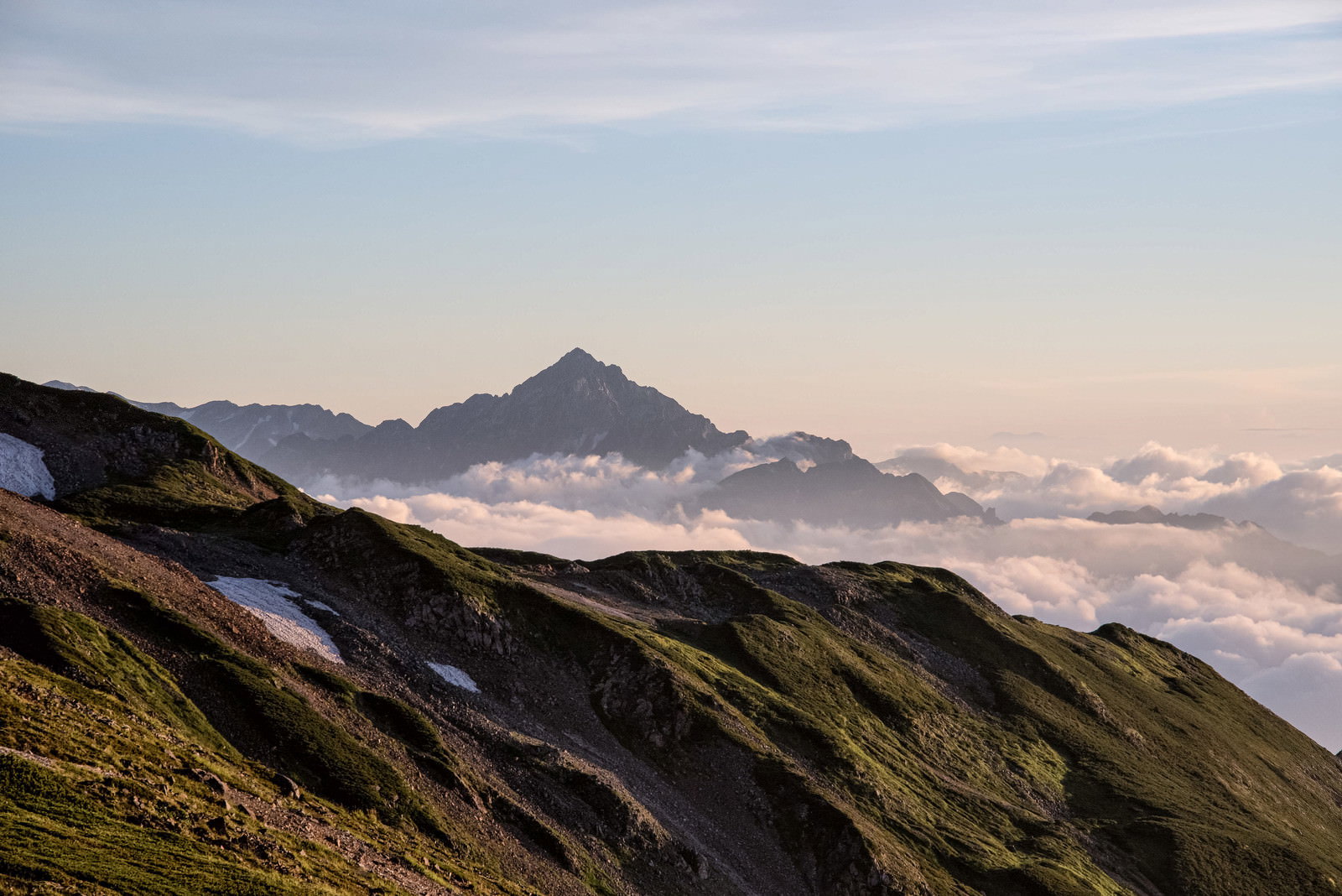 雲海の上に聳える剱岳が夕焼け空に染まる山岳風景
