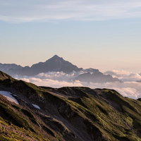 夕焼けに染まり始めた剱岳のキレット縦走路の写真