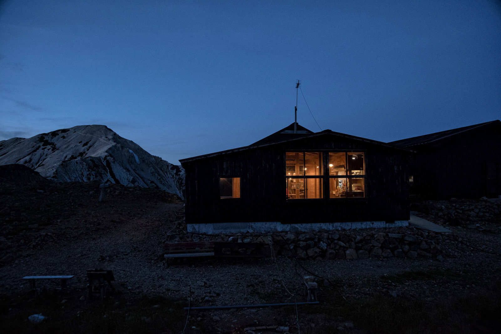 夕暮れの山間に佇む天狗山荘、窓から温かな光が漏れている