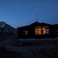 キレット縦走の天狗山荘、夕暮れ時に窓明かりが灯る山小屋の写真
