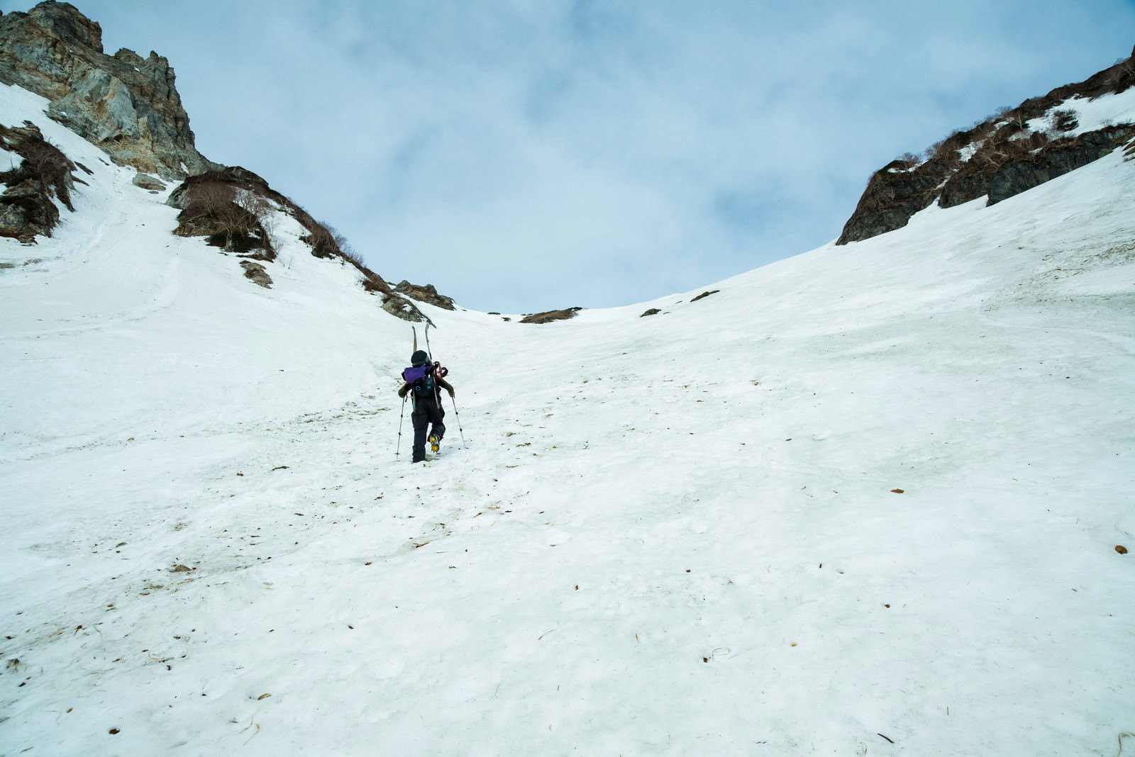 雪に覆われた山の斜面を歩く登山者の後ろ姿