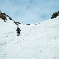 雪山の斜面をスキーで滑降する登山者の写真