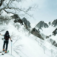 雪化粧した雪山を望むクロスカントリー中の男性の写真