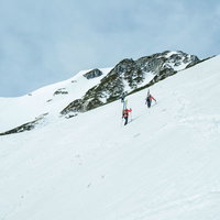 雪山に挑む登山者達の足跡と岩肌の山々、冬の登山風景の写真