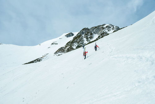 雪山に挑む登山者達の足跡と岩肌の山々、冬の登山風景