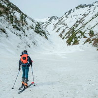 雪山の雪原を進む山スキーヤーの写真
