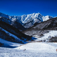 青空と雪山に囲まれた鹿島槍スキー場のゲレンデの写真