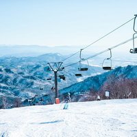 雪山のゲレンデを滑るスキーヤーとリフトの風景の写真