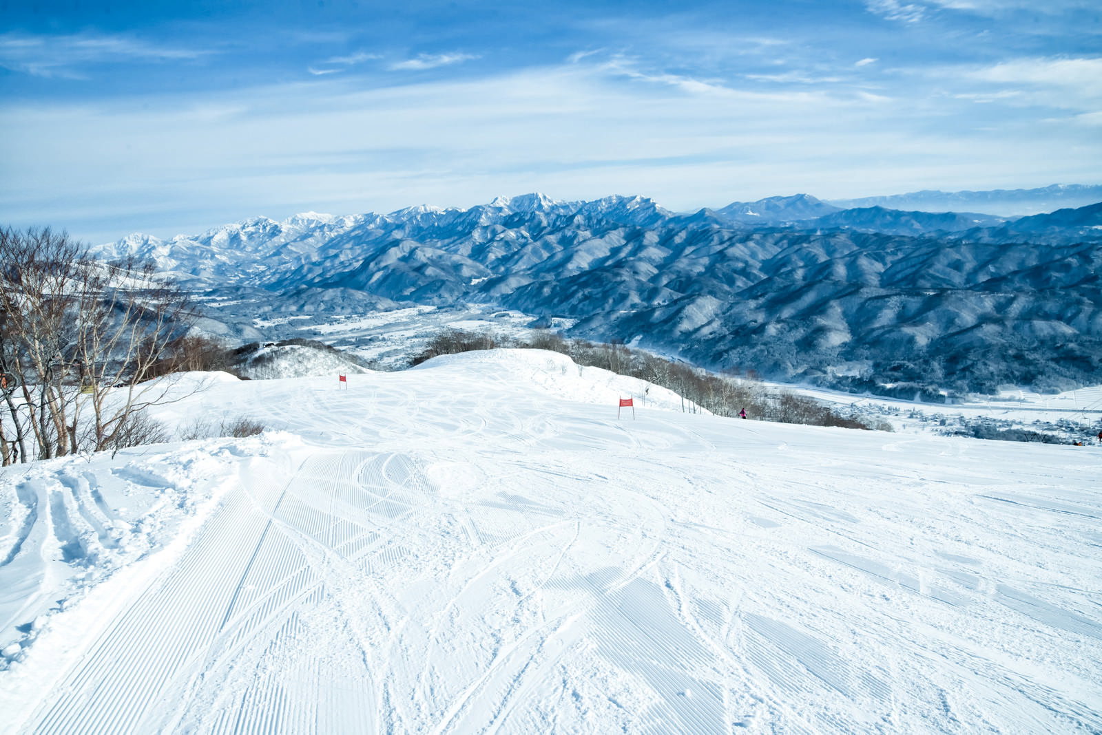 青空の下、白馬五竜スキー場の雪面に残るシュプール