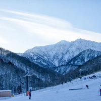 夕暮れ時のゲレンデとリフト、雪化粧した山々が連なる鹿島槍スキー場の写真