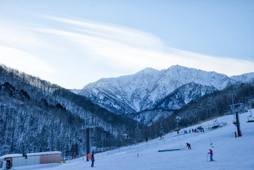 夕暮れ時のゲレンデとリフト、雪化粧した山々が連なる鹿島槍スキー場