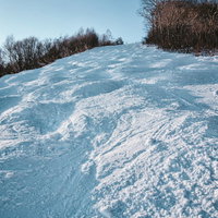 青空が広がるスキー場の凹凸のあるコースと積雪風景の写真