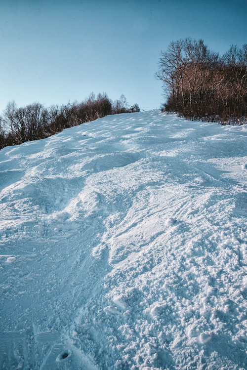 青空が広がるスキー場の凹凸のあるコースと積雪風景