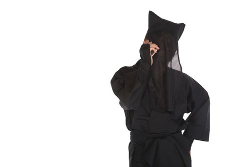 スマートフォンで通話する黒い衣装の匿名人物