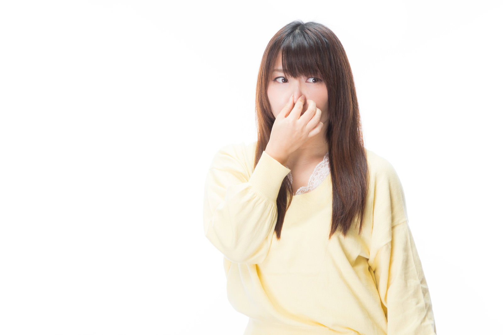 黄色い服を着た女性が手で鼻を覆い嫌がっている様子［モデル：Lala］