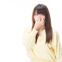 においに敏感に反応して鼻を押さえる女性の写真