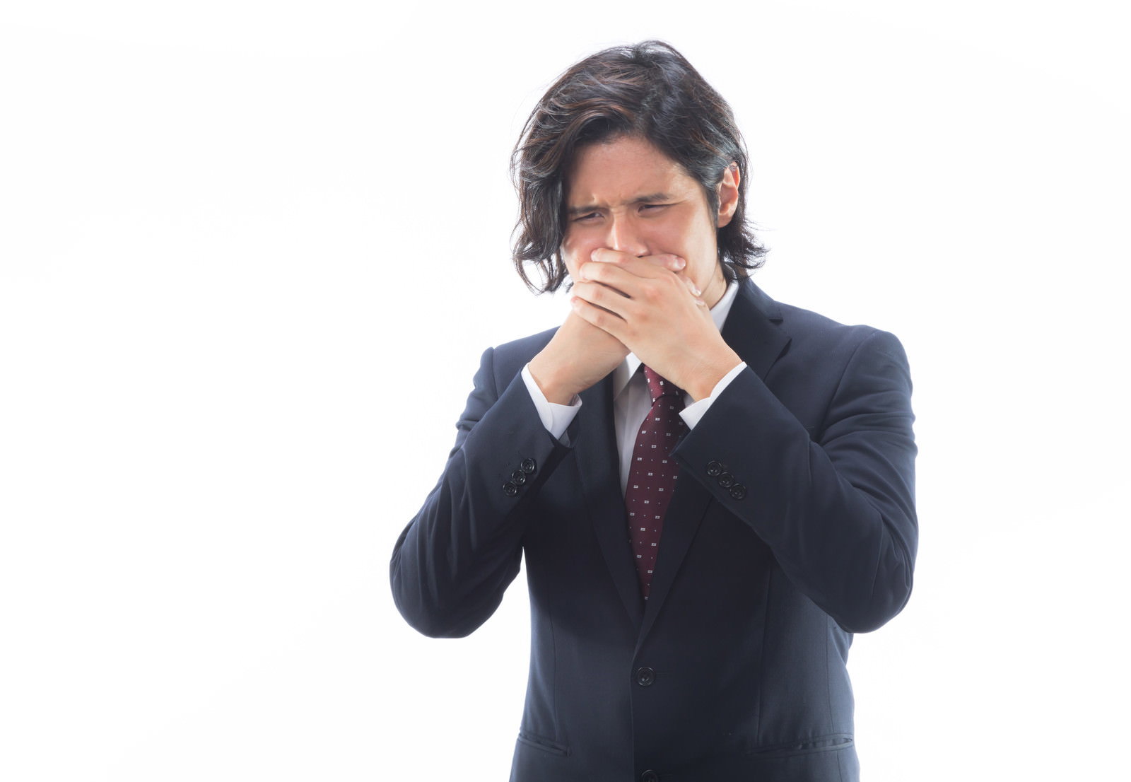 紺スーツの男性が両手で鼻と口元を覆い、眉間にしわを寄せている［モデル：竹田匡宏］
