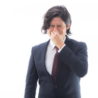 目がしみるほどの強烈なにおいを嗅いで顔をしかめる男性会社員の写真