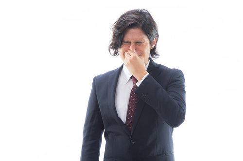 目がしみるほどの強烈なにおいを嗅いで顔をしかめる男性会社員