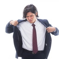 暑い季節に汗をかいて上着を脱ぐサラリーマンの写真
